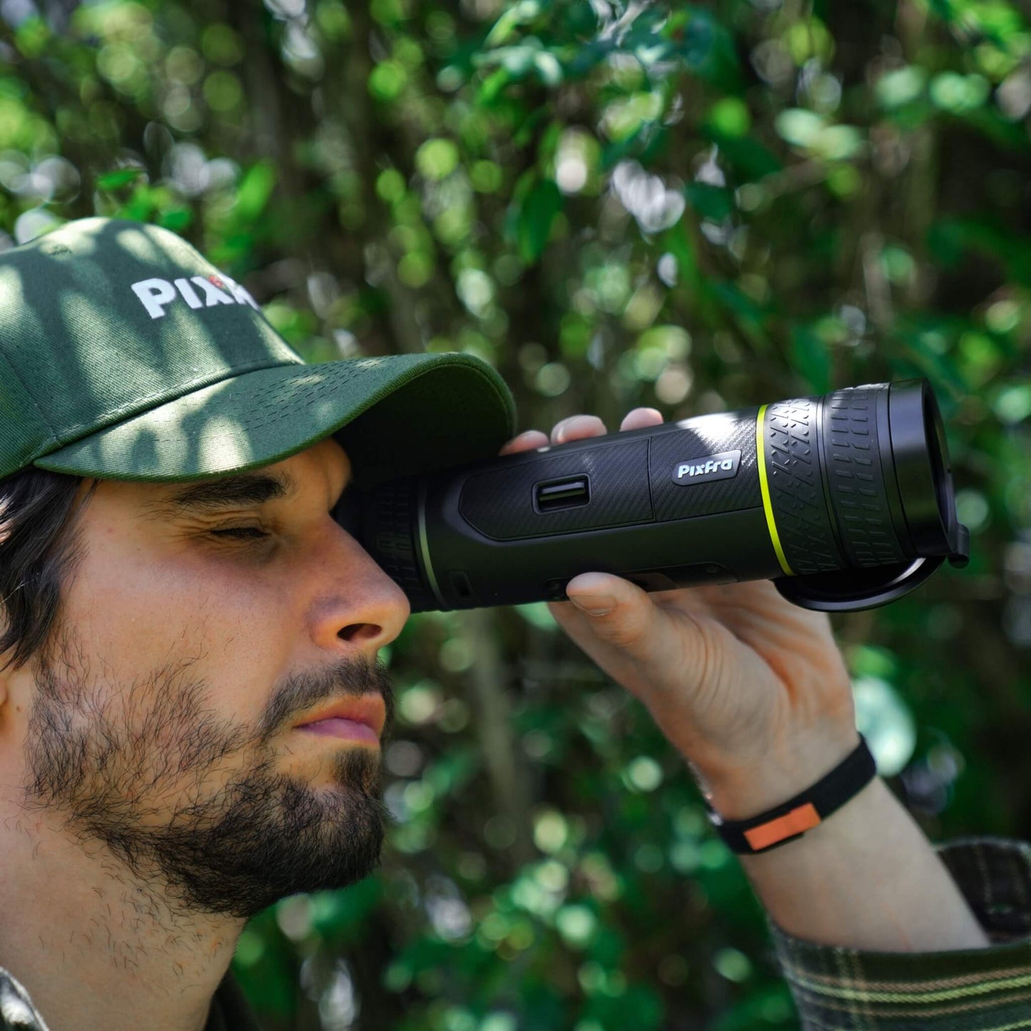 Person holding Pixfra Sirius S650 up to their eye showing the side profile, green rings, and ergonomic grip during use.