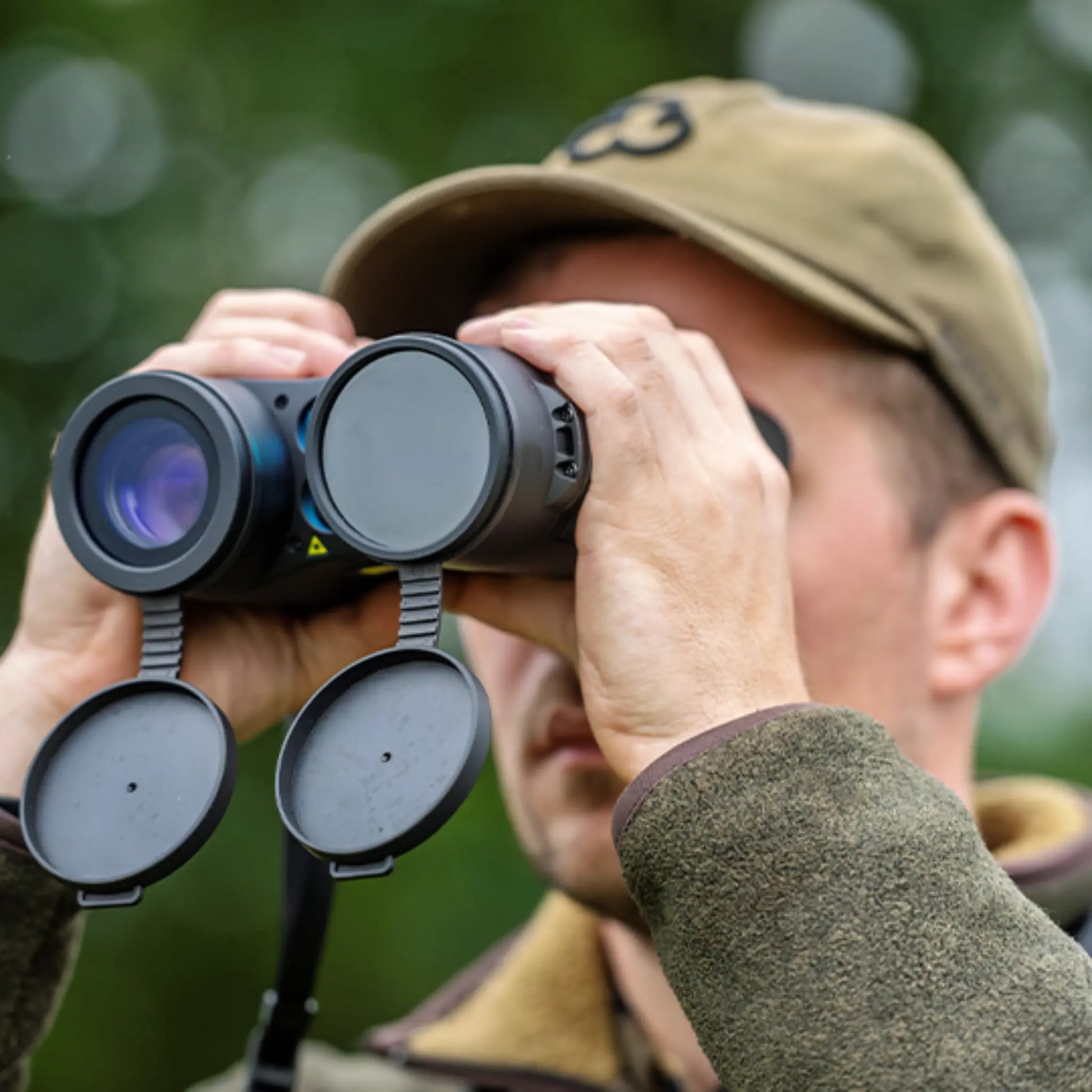 Client turned left holding the InfiRay Gemini GEH50R thermal imaging binoculars, showcasing the dual lenses, control buttons, and ergonomic design.