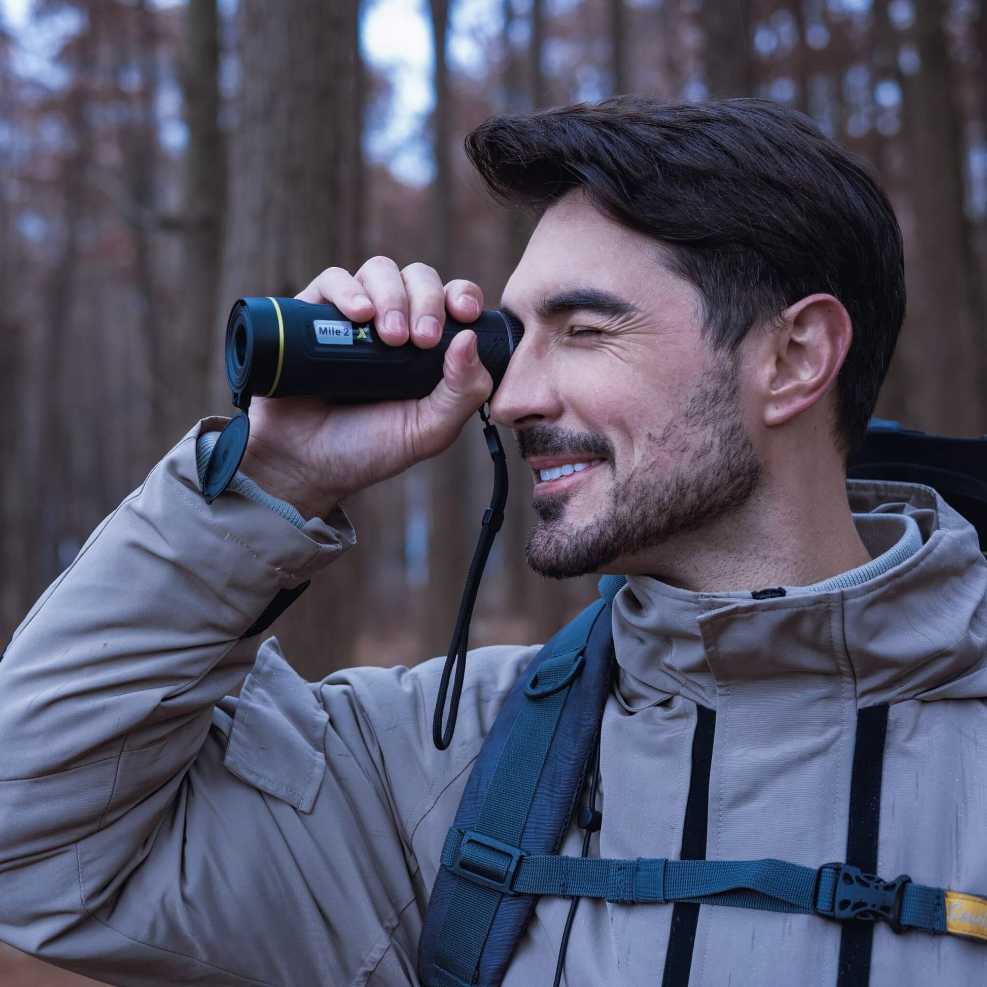 A man holding the Pixfra Mile 2 M413 Thermal Monocular to his eye, demonstrating its compact handheld ergonomics and lightweight portable design during field use.