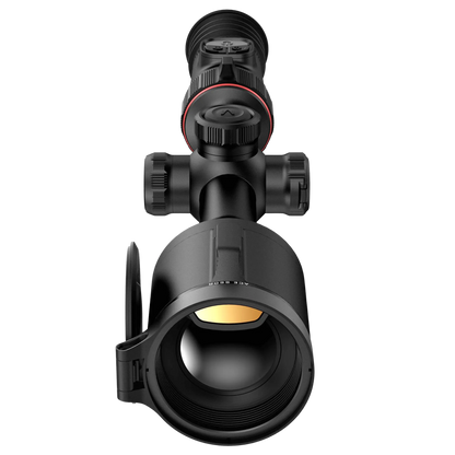 The Nocpix ACE S60R, viewed directly from the front, clearly showing its large 60mm objective lens with an orange tint, and the lens cap flipped open. The black tube-style body and control turrets are also visible.