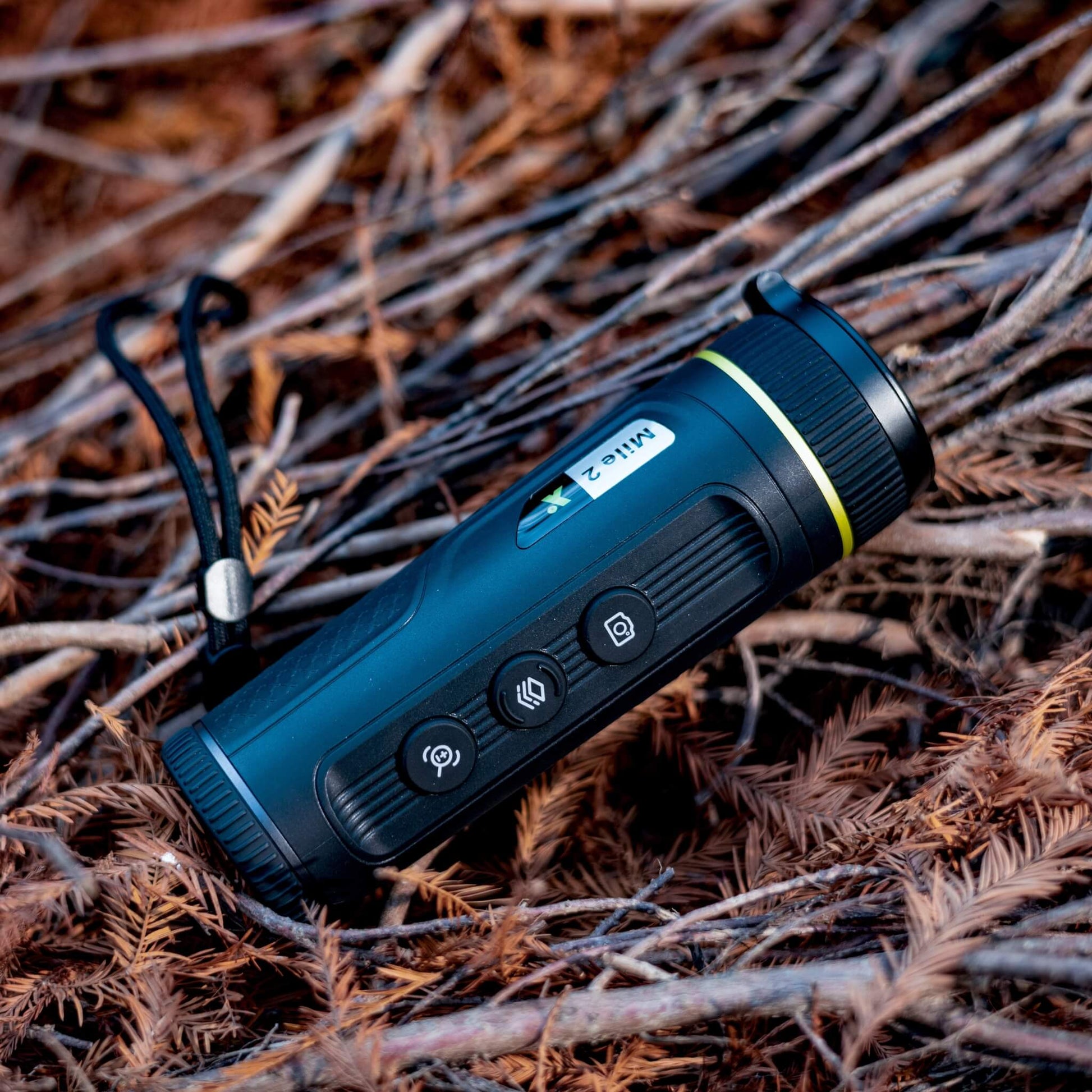 The Pixfra Mile 2 M419 Thermal Monocular sitting in an open field, highlighting its rugged IP67-rated construction and 1,000m detection capability for long-range outdoor surveillance.