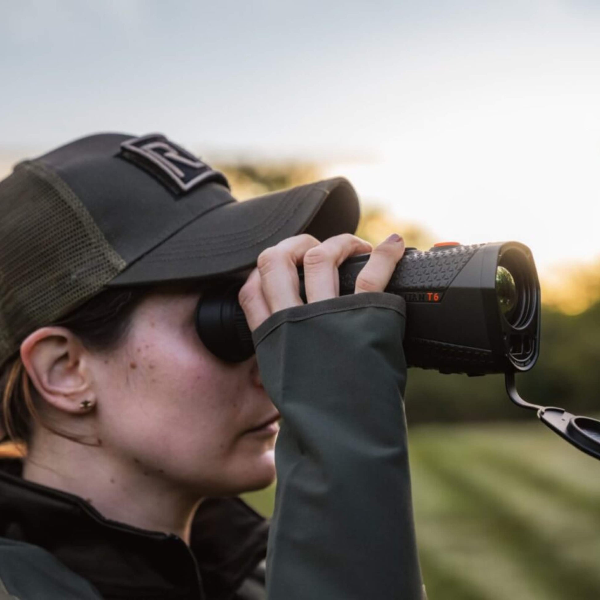 RIX Titan T6 Thermal Monocular being used in a field by a lady with a hat, highlighting its application for nature observation, birding, and wide-area scouting in rugged environments