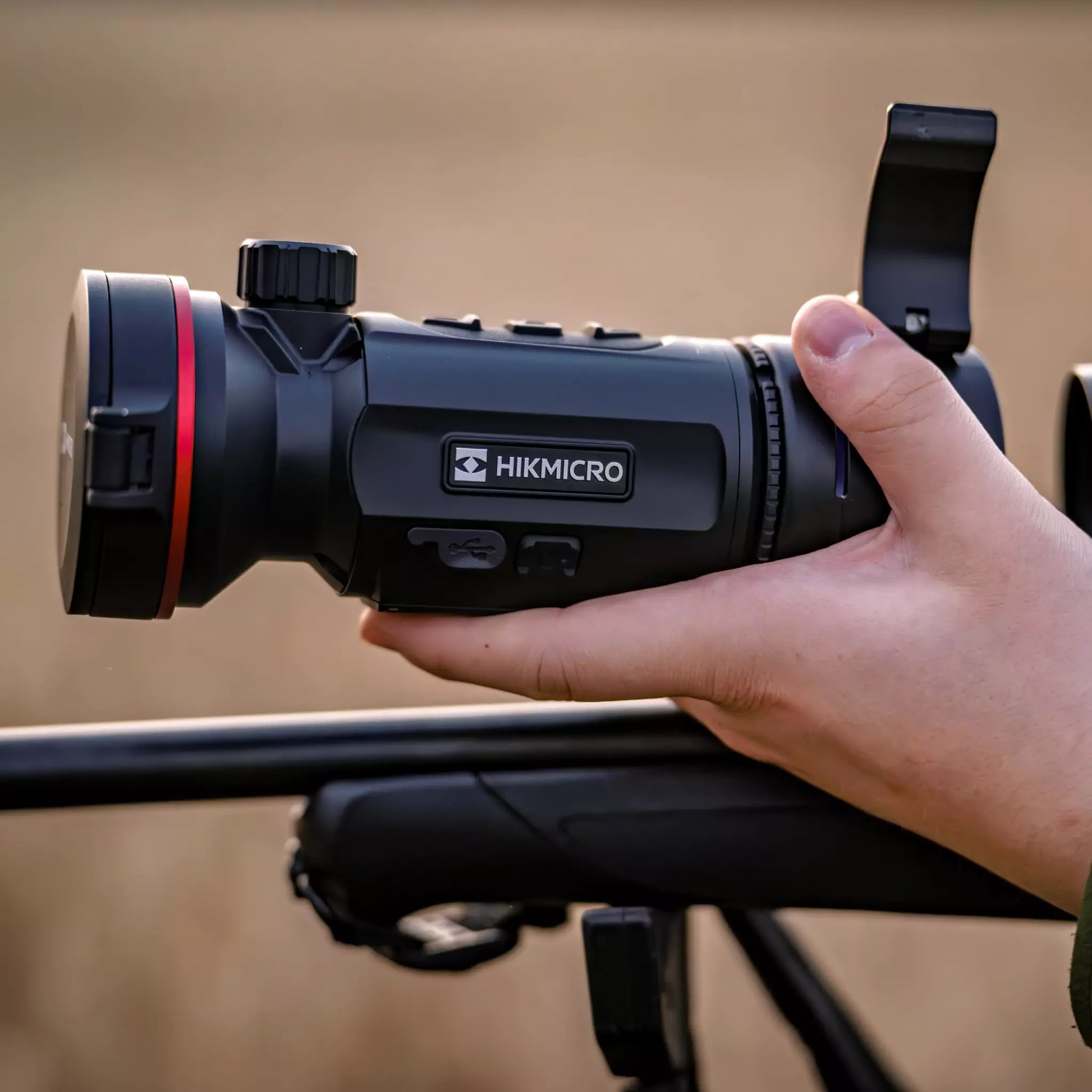 The HIKMICRO Thunder TQ50CL 3.0 thermal imaging clip-on scope mounted on a hunting platform, used for observation in a daytime field environment.