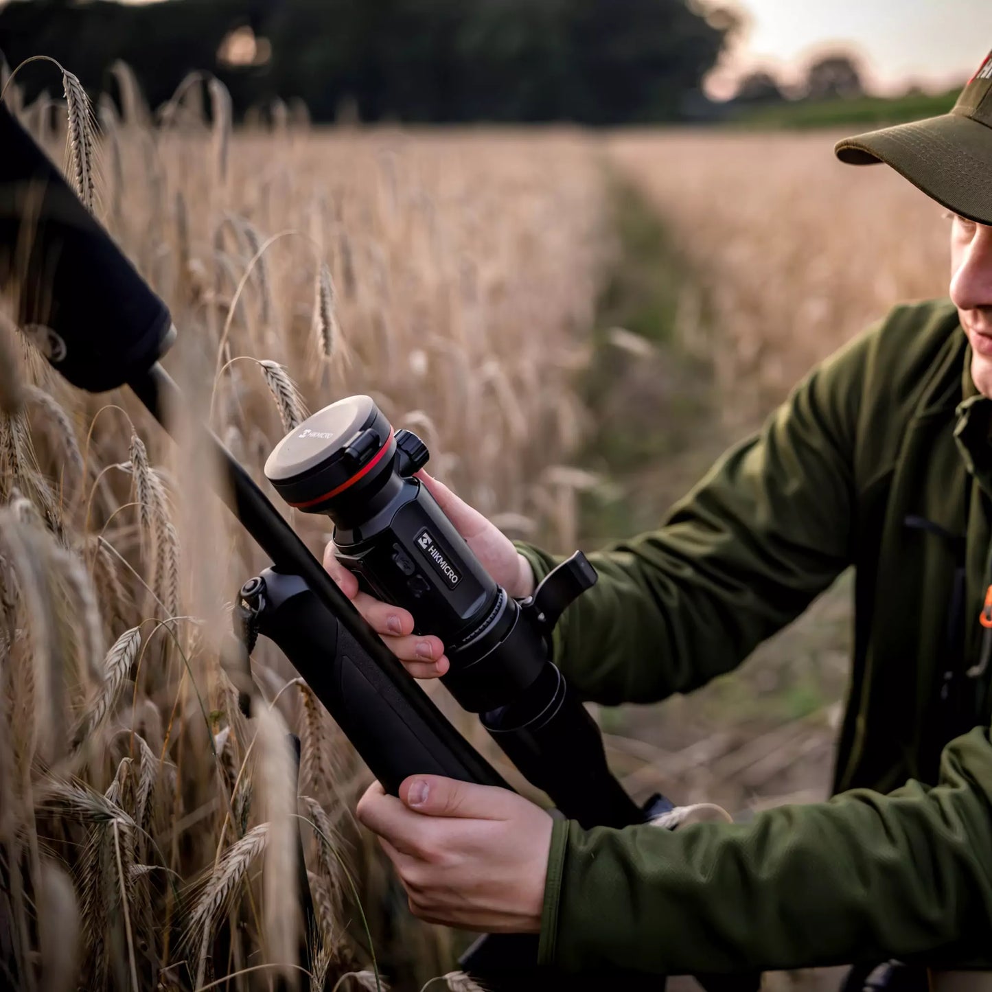 The HIKMICRO Thunder TQ50CL 3.0 thermal imaging clip-on scope being mounted on a day scope, used for observation in a daytime field environment.